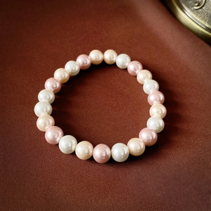 Détail d'un bracelet de perles vintage avec perles blanches, roses et crème sur tissu brun