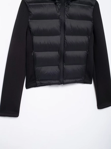 Detail of black hooded jacket with glossy nylon panels and hidden zipper pockets
