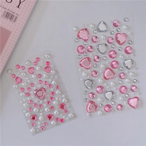 Flat lay of pink heart-shaped crystal gemstone and pearl stickers for DIY decoration