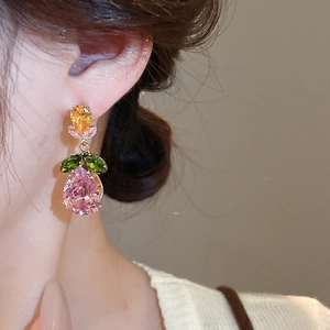 Detailed close-up of zircon drop earrings with yellow and pink stones on a model
