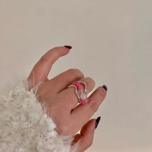 Detail view of handmade beaded ring with pink and white stones on wavy silver band