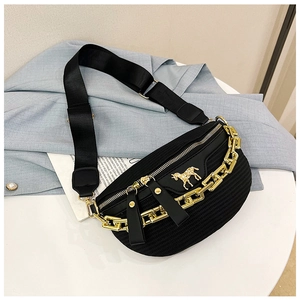 Close-up of black textured chest bag with golden chain detail and horse logo on light fabric
