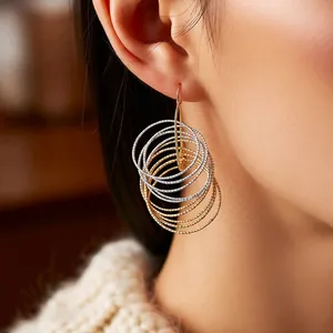 Multilayer gold and silver intertwined hoop earrings with striped texture on a model