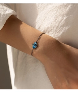 Detail of Hamsa Hand and Evil Eye charm on black S925 silver bracelet for women