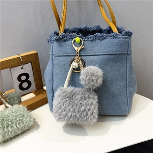 Detailed view of grey plush keychain with blue denim bag charm and pearl accents