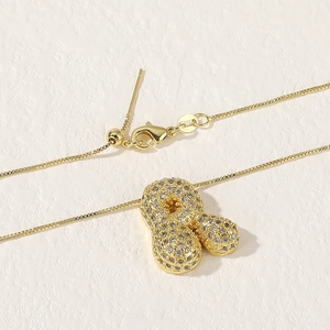 Detail of 18K gold bubble letter pendant necklace with micro-pave zirconia stones