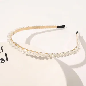Detail of elegant triple-row white pearl headband with gold metal frame on a white tray