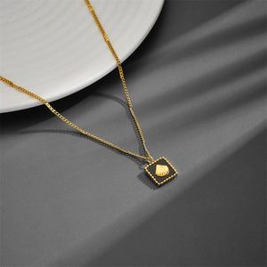 18K gold plated titanium necklace with square shell pendant on an elegant jewelry dish