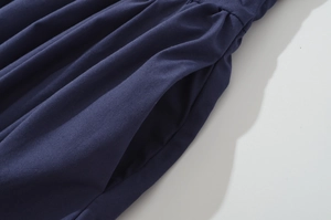 Detail view of waist pleats and side hidden pocket on a dark blue maxi dress