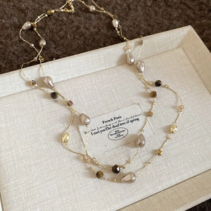 Detailed flat lay of 18k gold plated tiger eye and baroque pearl long necklace