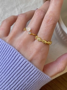 Nahaufnahme eines s925 Silber-Ring-Sets in Gold mit weißer Rose und Muschel-Design am Finger