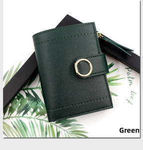 Macro detail of deep green leather wallet with gold ring buckle and secure zipper