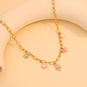 Gold chain necklace with pink butterfly, tulip charms and faux pearls on beige background