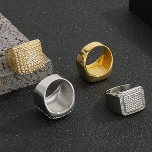 Vista macro di anelli quadrati hip hop in oro e argento con strass su sfondo nero testurizzato