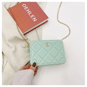 Close-up of mint green PVC jelly bag featuring diamond quilted texture and floral gold charm