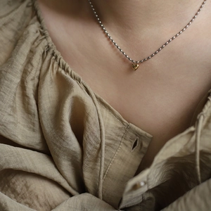 Minimalist chic silver beaded necklace with tiny gold heart pendant worn on model