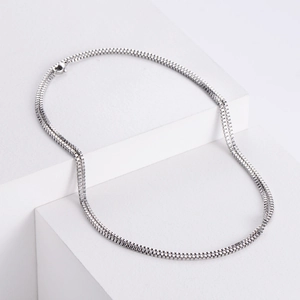 Silver stainless steel box chain necklace displayed on minimalist white geometric stands