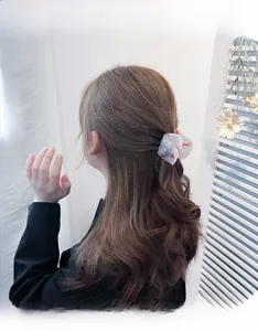 Detail of white baseball pattern hair scrunchie with red stitching on model hair