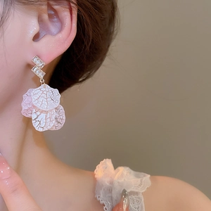 Close-up of model wearing shell petal tassel earrings with zircon-studded Z-shaped metal