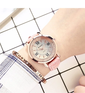 Detail of pink leather watch with rose gold case and Roman numeral dial on wrist
