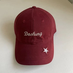 Close-up of Dashing script embroidery and plaid star patch on a dark red cotton baseball cap