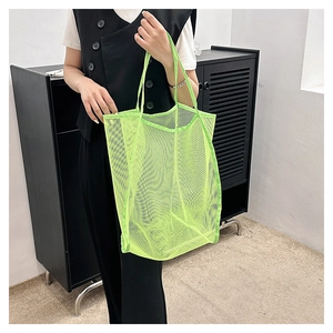 Model holding a large capacity neon green mesh tote bag with reinforced handles