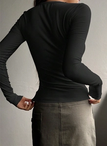 Rear view of black ribbed knit long sleeve top showing slim fit and fabric texture