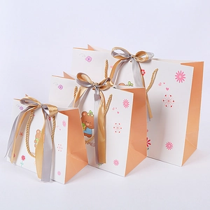Three-piece set of cartoon bear gift bags with golden rope handles and decorative ribbons