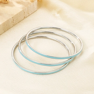 Detailed stack of three silver stainless steel bangles with light blue enamel inlay