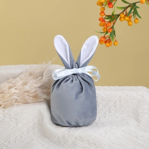 Detailed view of gray velvet rabbit ear gift bag with silk ribbon on knit fabric