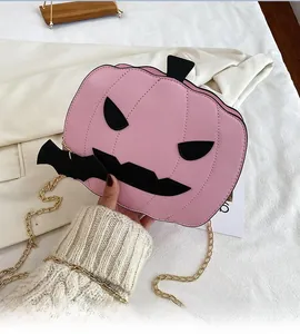 Detailed view of a pink pumpkin crossbody bag with black bat accents and gold chain strap