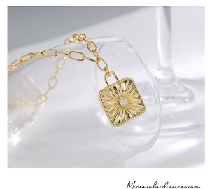 Detail view of gold sunburst pendant with opal stone inlay on a clear glass prop