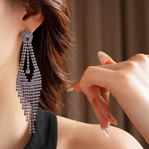 Vue macro de longues boucles d'oreilles à pompons violets avec strass sur le mannequin