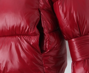 Close-up of shiny red padded jacket showing quilted stitching and side pocket detail