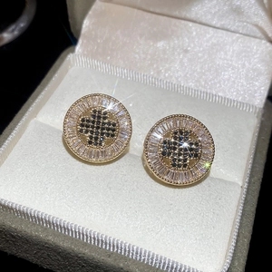 Close-up of gold plated round stud earrings with black and white zircon stone setting