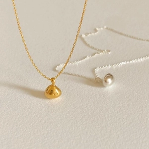 Close-up of minimalist S925 sterling silver bean pendant necklaces in gold and silver