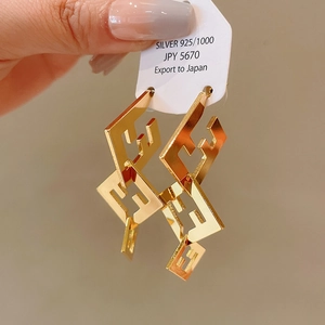 Macro shot of geometric double-F cutout earrings in gold finish on 925 silver studs