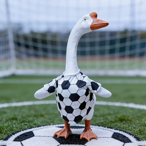 Detailed view of white porch goose statue in soccer uniform on a realistic grass field