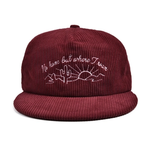 Detailed white embroidery of desert elements on burgundy corduroy baseball cap surface