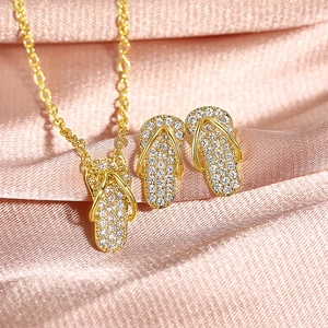 Macro-opname van goudkleurige slipper-ketting en oorbellen met zirkonia op zijden stof