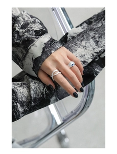 Detailed close-up of a silver irregular S925 ring set with a blue zircon on model's hand