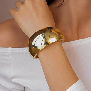 Polished gold wide cuff bracelet with irregular texture shown on a female model wrist