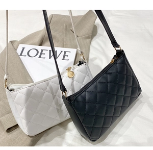 Close-up of quilted rhombus pattern on black and white underarm bags with gold zippers