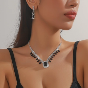 Close-up of silver-toned necklace and earrings set with large black stones on a model