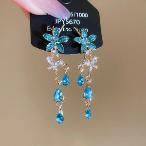 Close-up of sparkling blue crystal flower earrings with gold finish on a display card