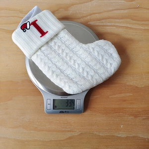 Macro view of white knitted Christmas stocking showing 33.4g weight on a kitchen scale