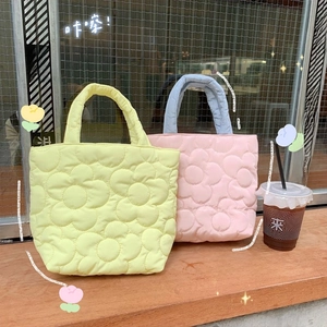 Detailed view of quilted cotton tote bag with flower pattern on a wooden bench
