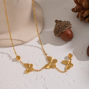 Exquisite gold butterfly necklace with round beads on elegant beige display stand