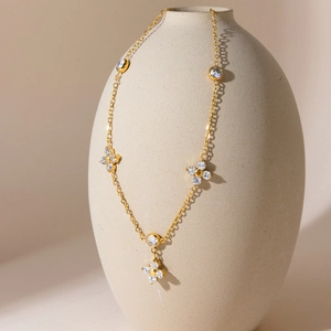 Elegante goldene Kleeblatt-Halskette mit Zirkonia auf einer ästhetischen Keramikvase