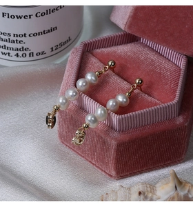 Dettaglio di orecchini con perle naturali su scatola di velluto rosa con decorazione
